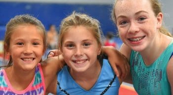 three girls with arms around each other at gymnastics camp