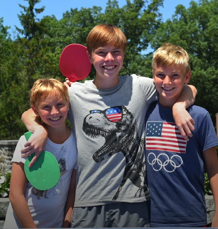 three boys holding ping pong paddles