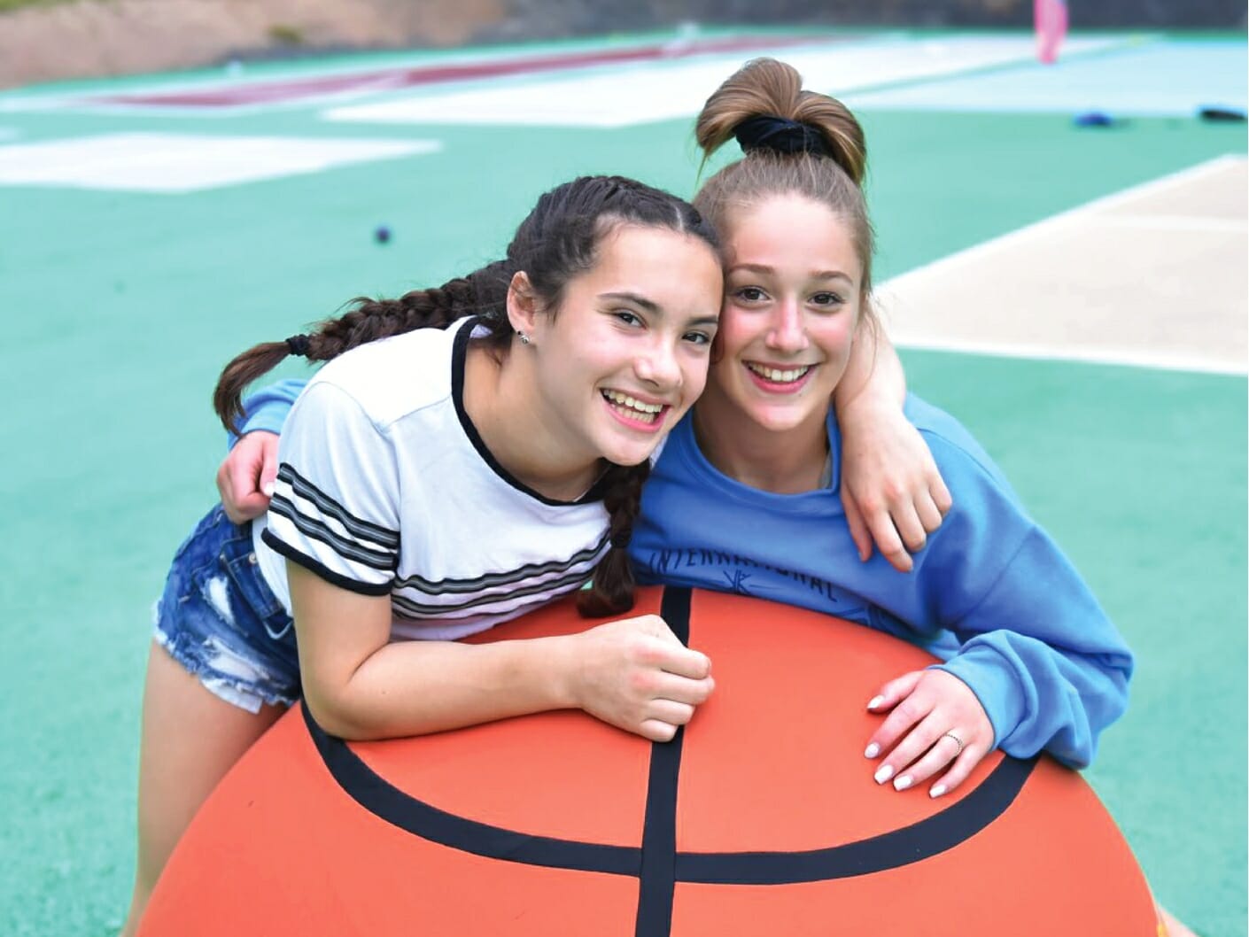 girls leaning on extra large inflatable basketball