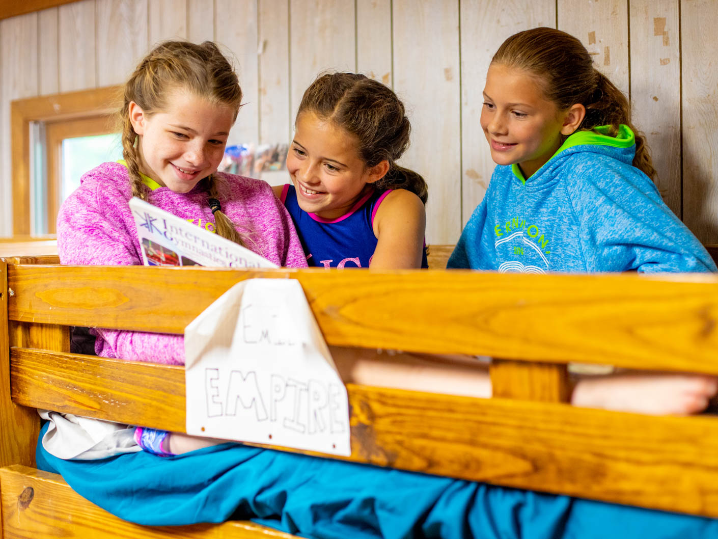 girls sitting atop one of the bunk beds in a cabin