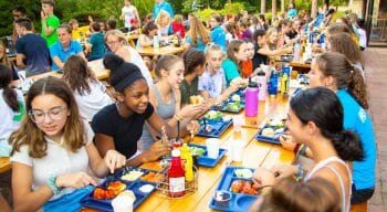 large group of kids and adults eating at picnic tables