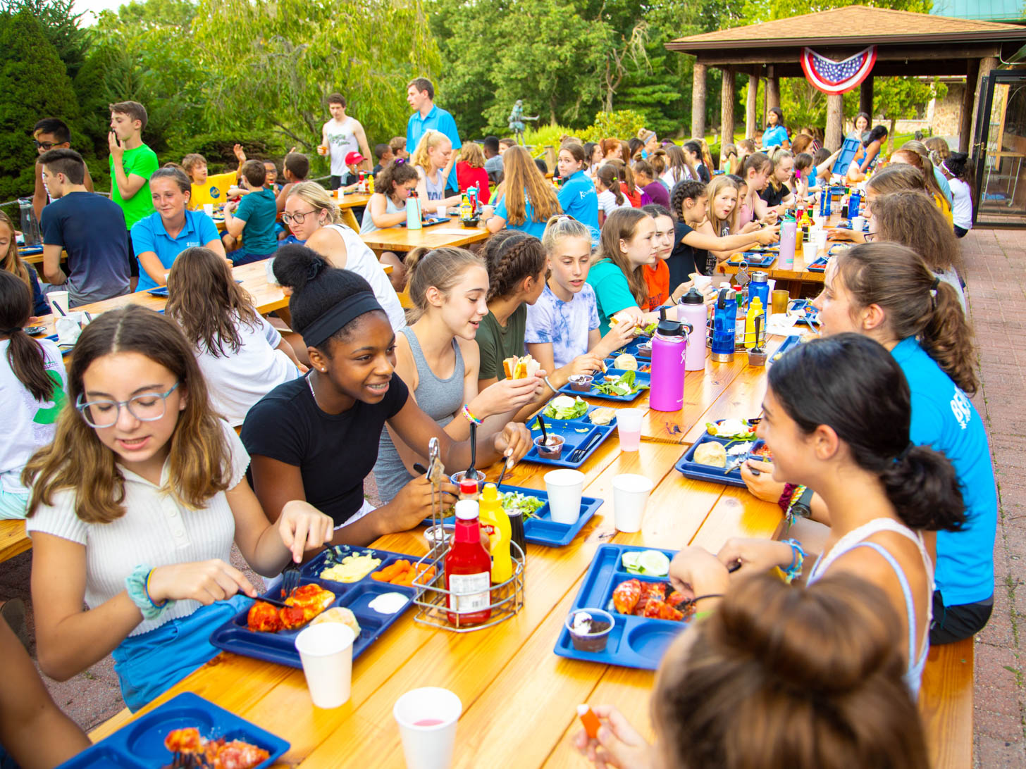 large group of kids and adults eating at picnic tables