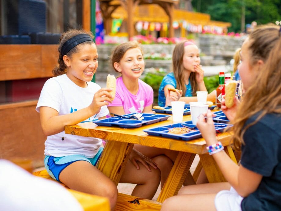 campers eating and socializing outside at the picnic tables
