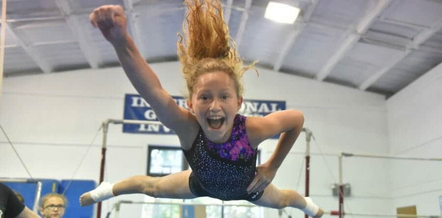 girl leaping through air at gymnastics camp