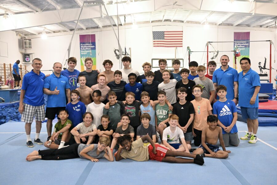 a group of men and boys posing for a photo in the gymnastics camp.